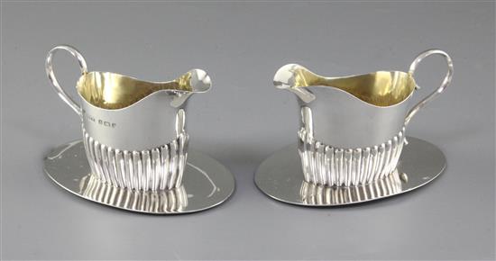 A pair of Edwardian demi fluted silver cream jugs on integral stands, length 115mm, weight 6.5oz/205grms.